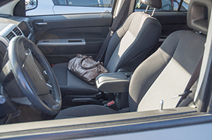 A brown purse sits on a car seat