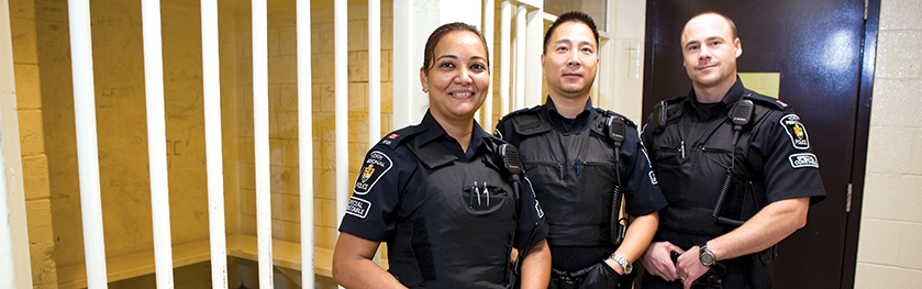 Three officers in front of a white bars