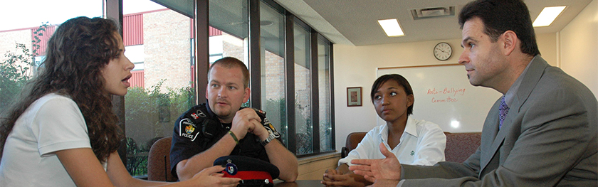 A female student talks to a police officer and two other adults