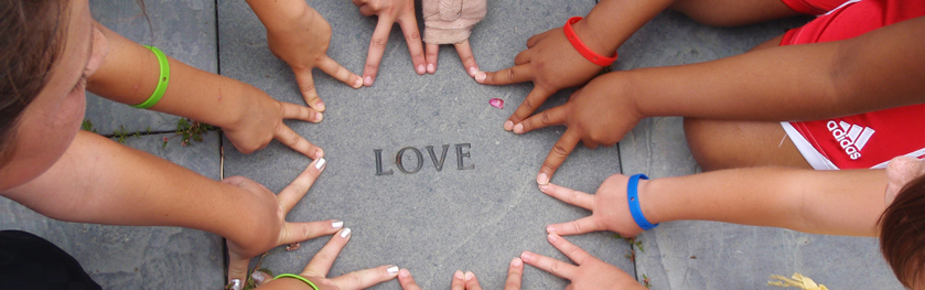 Children's fingers form a circle with the word love in the middle