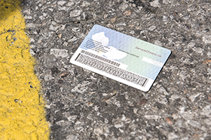 A piece of identification lies on an asphalt surface