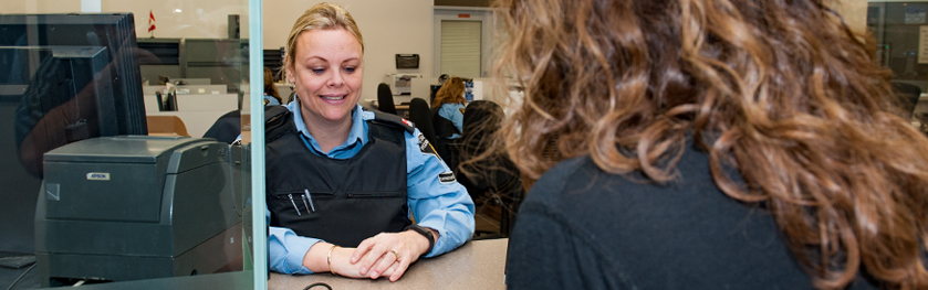 A woman in a police uniform smiles behind a counter 