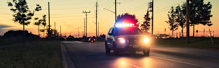 A police cruiser speeds by with emergency lights on