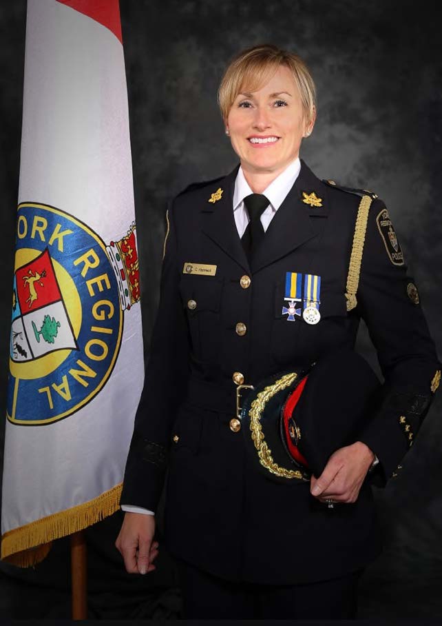 A woman in a police uniform holds a police hat