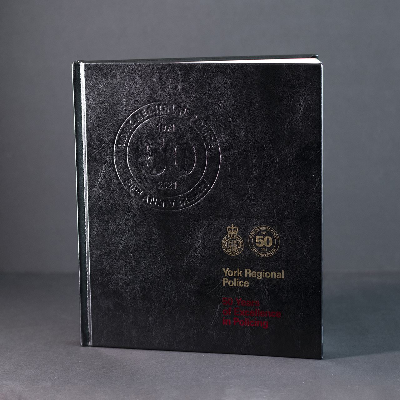 A black, leather bound book with gold and red foil text