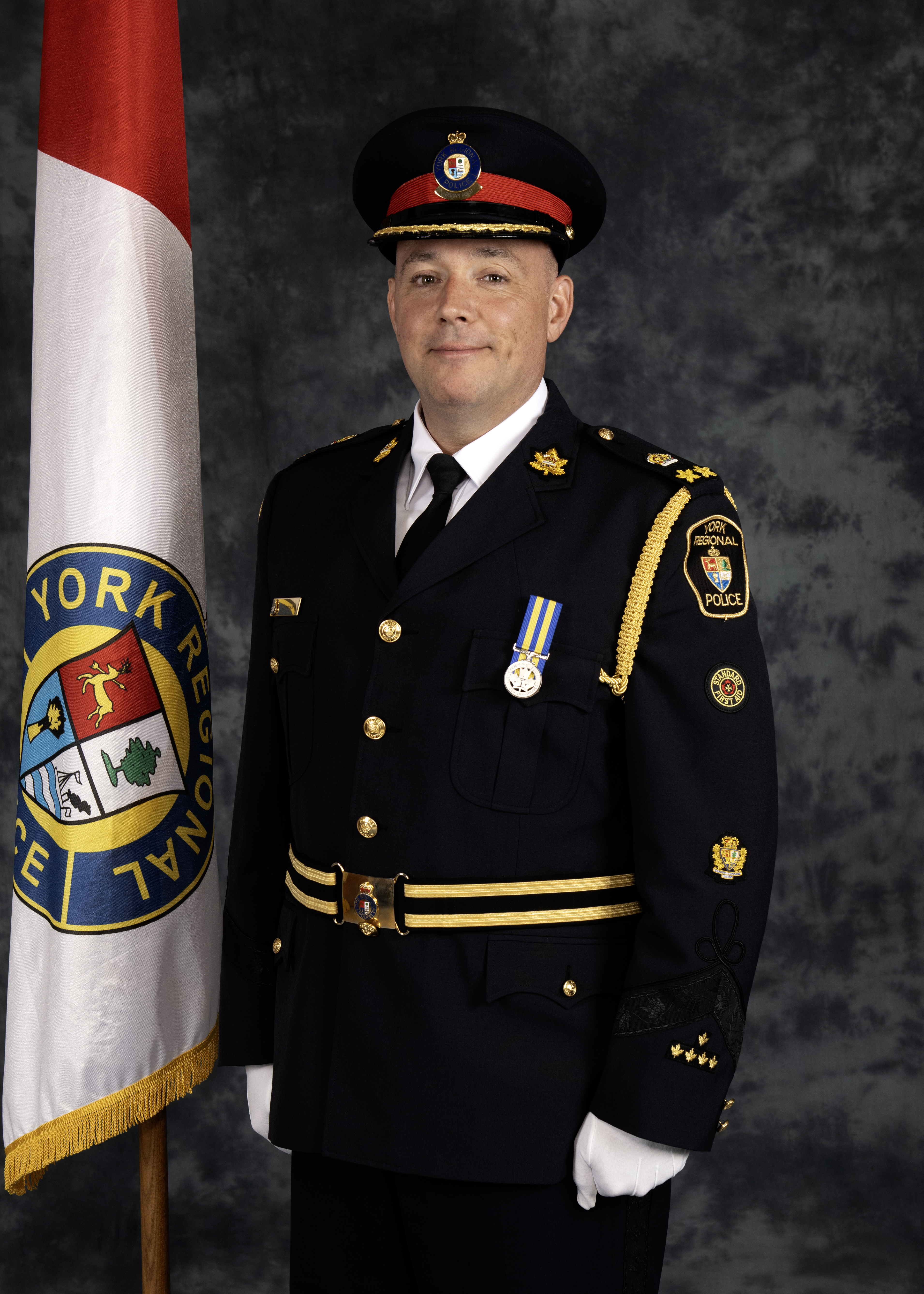 A man in a police uniform stands next to a flag