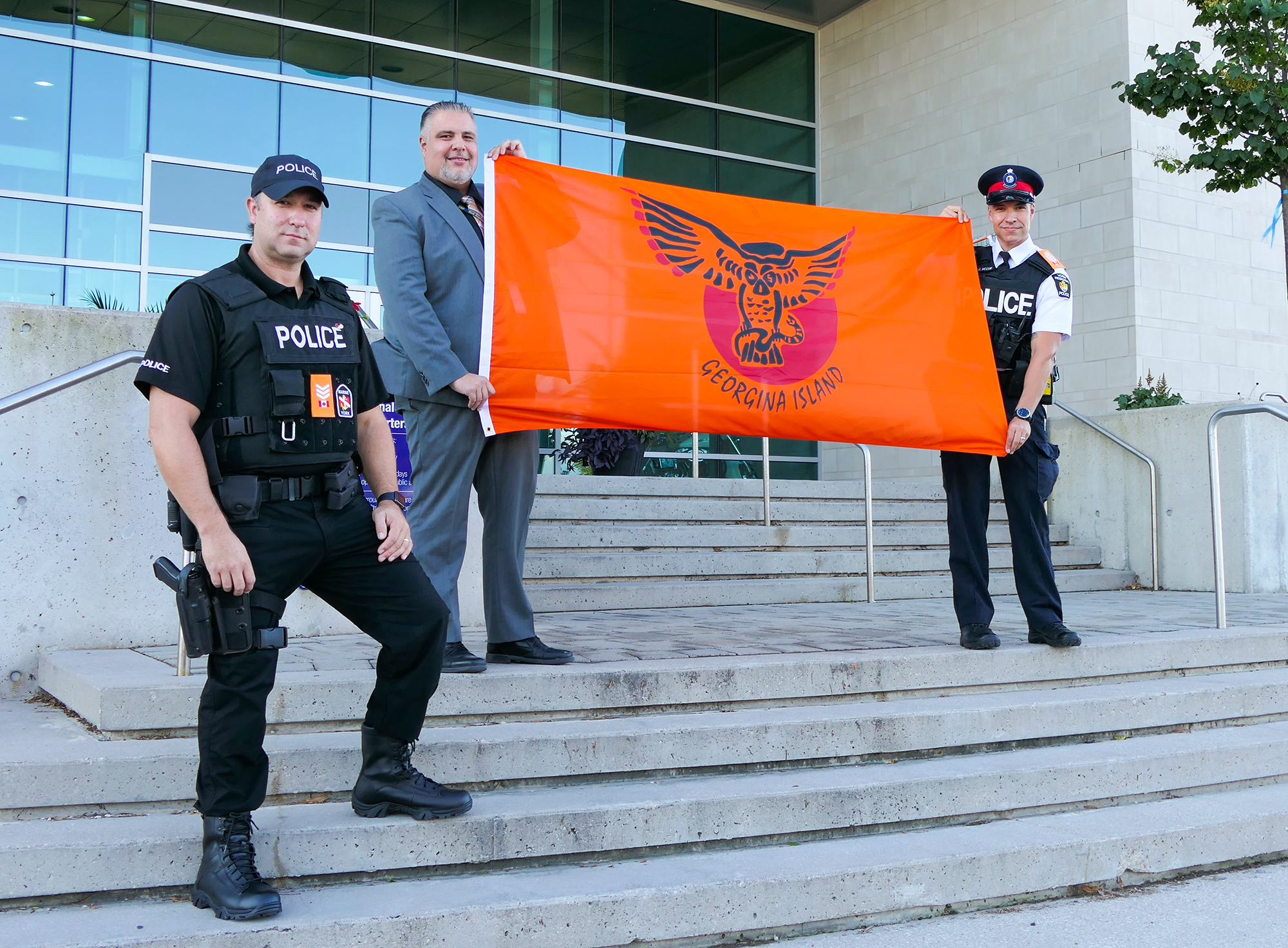 Three male officers with an orange Indigenous flag