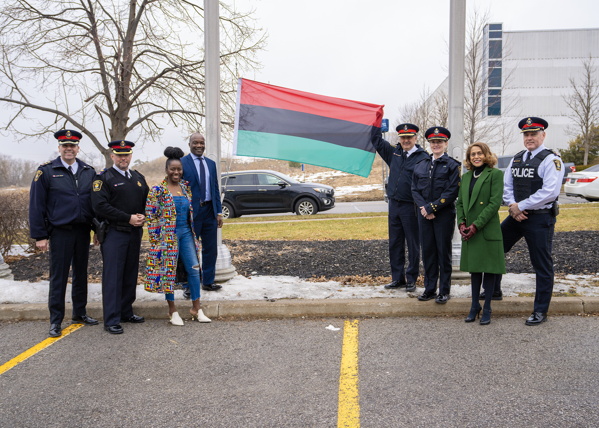 A group of people stand next to a flag with green, red and black stripes