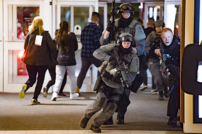 Police run into a doorway while others run in another direction.