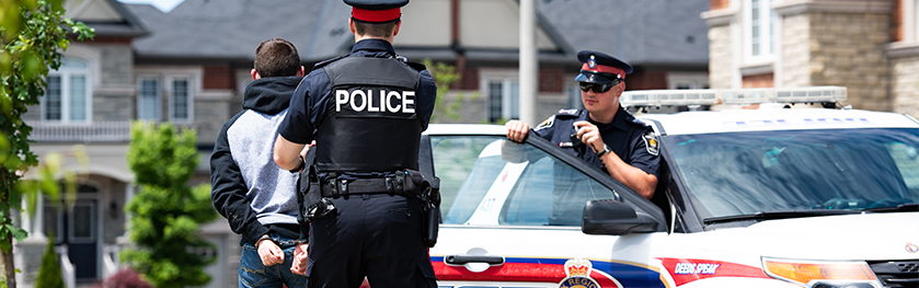 A man in a police uniform walks with another man in handcuffs