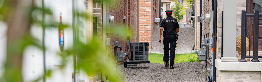 A man in a police uniform walks between two houses