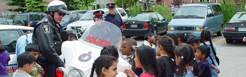 An officer on a motorcycle talks to a group of students