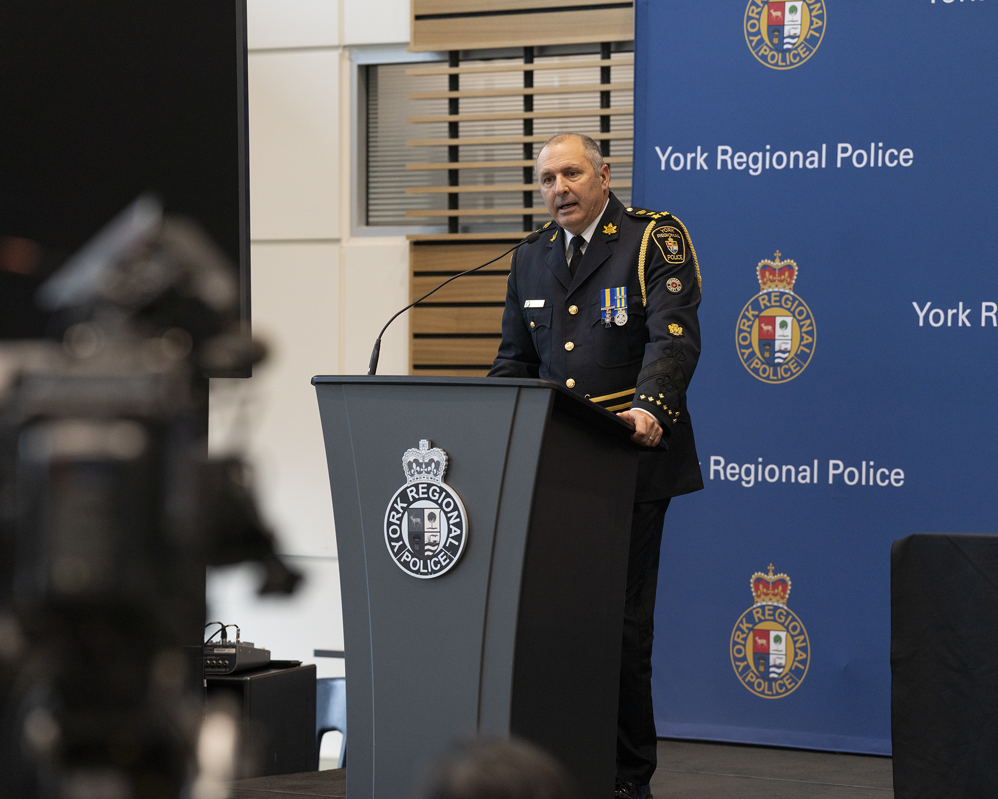 A man in a police uniform speaks at a podium