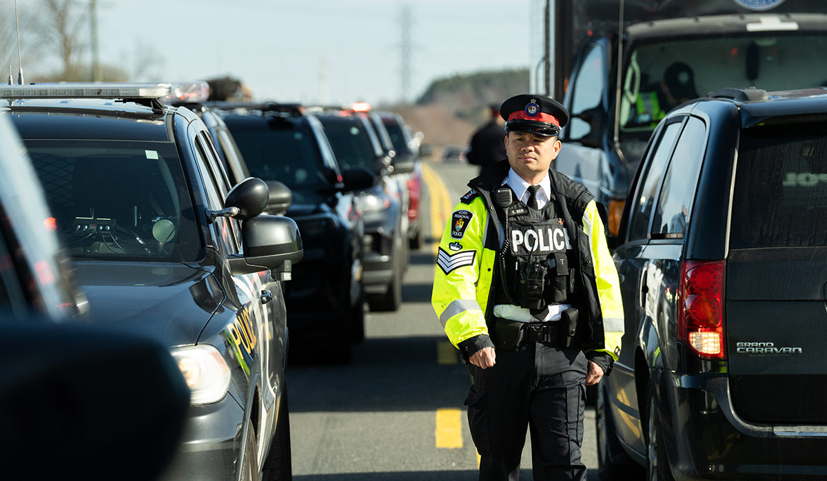 A man in a police uniform walks past lines of traffic