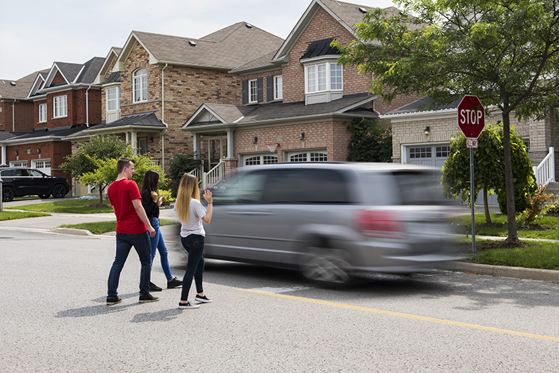 A group of people watch a car speed by a stop sign