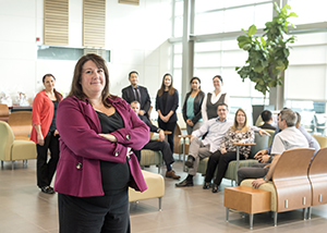 A woman wearing a blazer stands with a large group of people