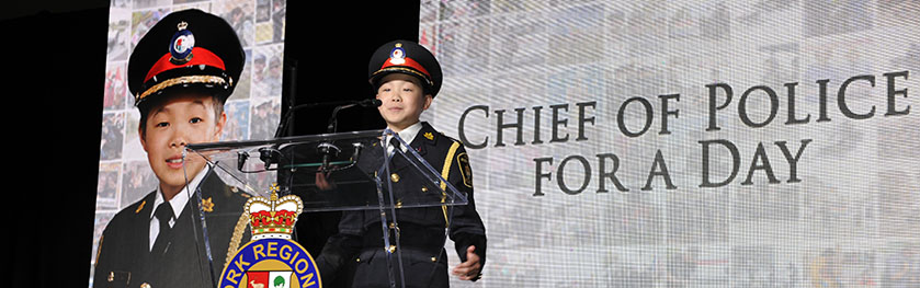 A youth in a Chief of Police uniform speaking at a podium