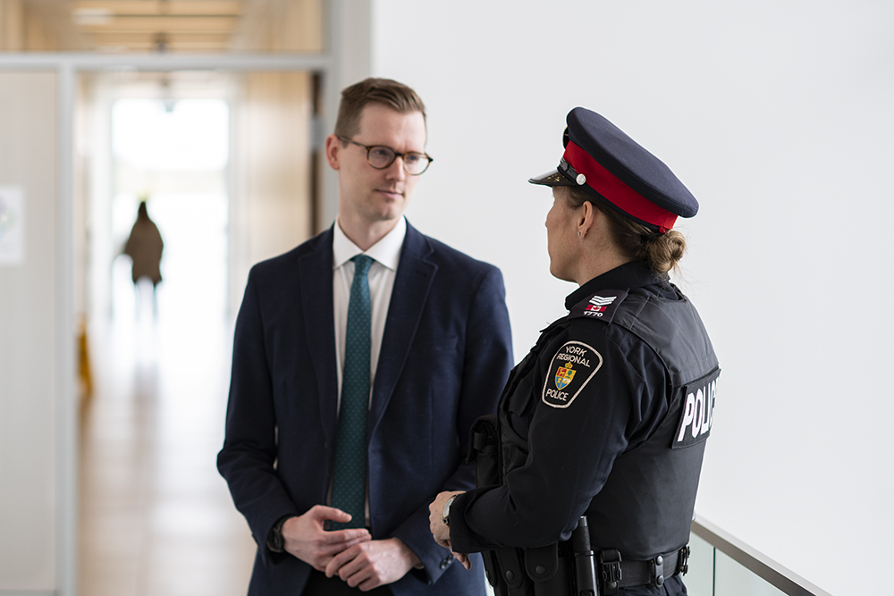 A man in a suit speaks with a woman in a police uniform
