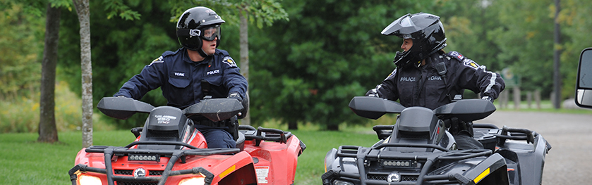 Two drivers sit on ATVs