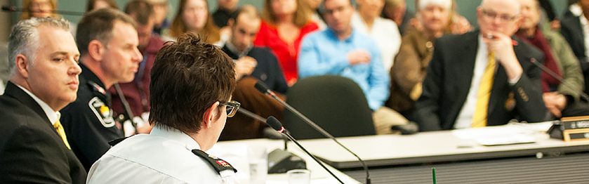 A woman speaks at a microphone in front of a crowd