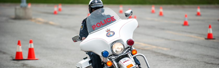 An officer rides a motorcycle through pylons