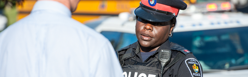 An officer speaks to a man in front of a school bus