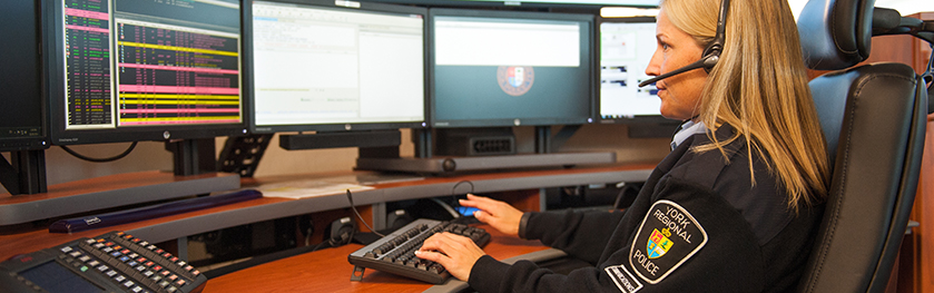 An operator speaks on a headset while looking at monitors