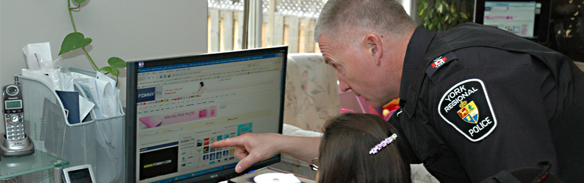 Officer is pointing to a computer screen to show a girl safety tips