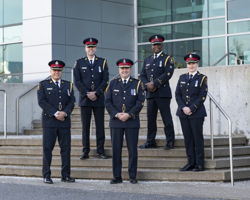 A group of people wearing formal police uniforms stand on a staircase