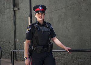 A woman in a police uniform stands next to a building