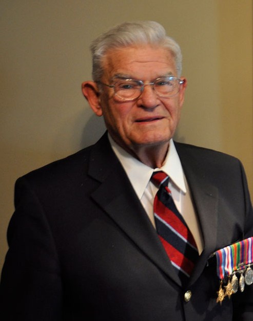 A man in a suit wears medals on his chest