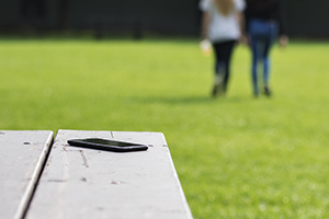 A phone lies on a picnic table while two women walk in the distance