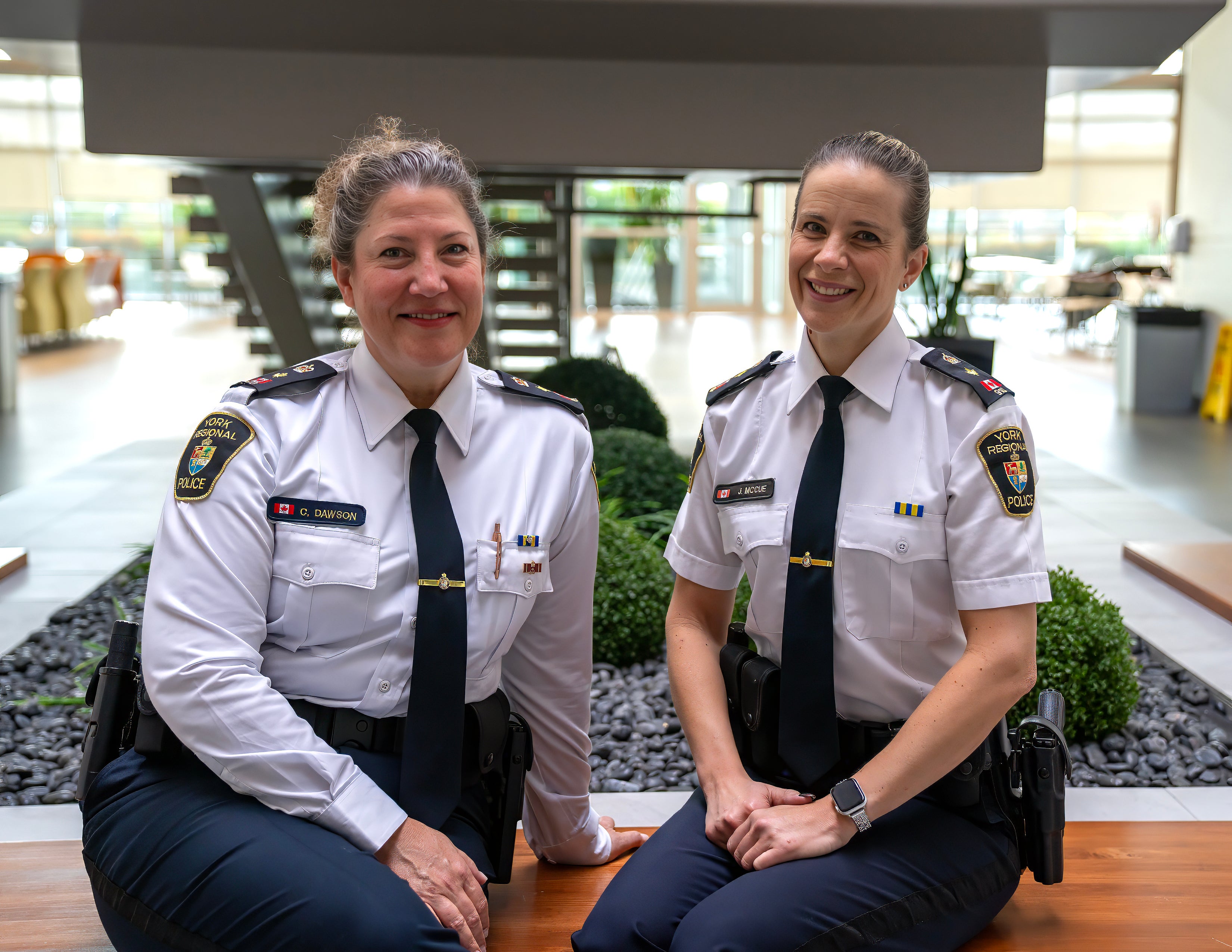 Two female officers sit in an atrium smiling
