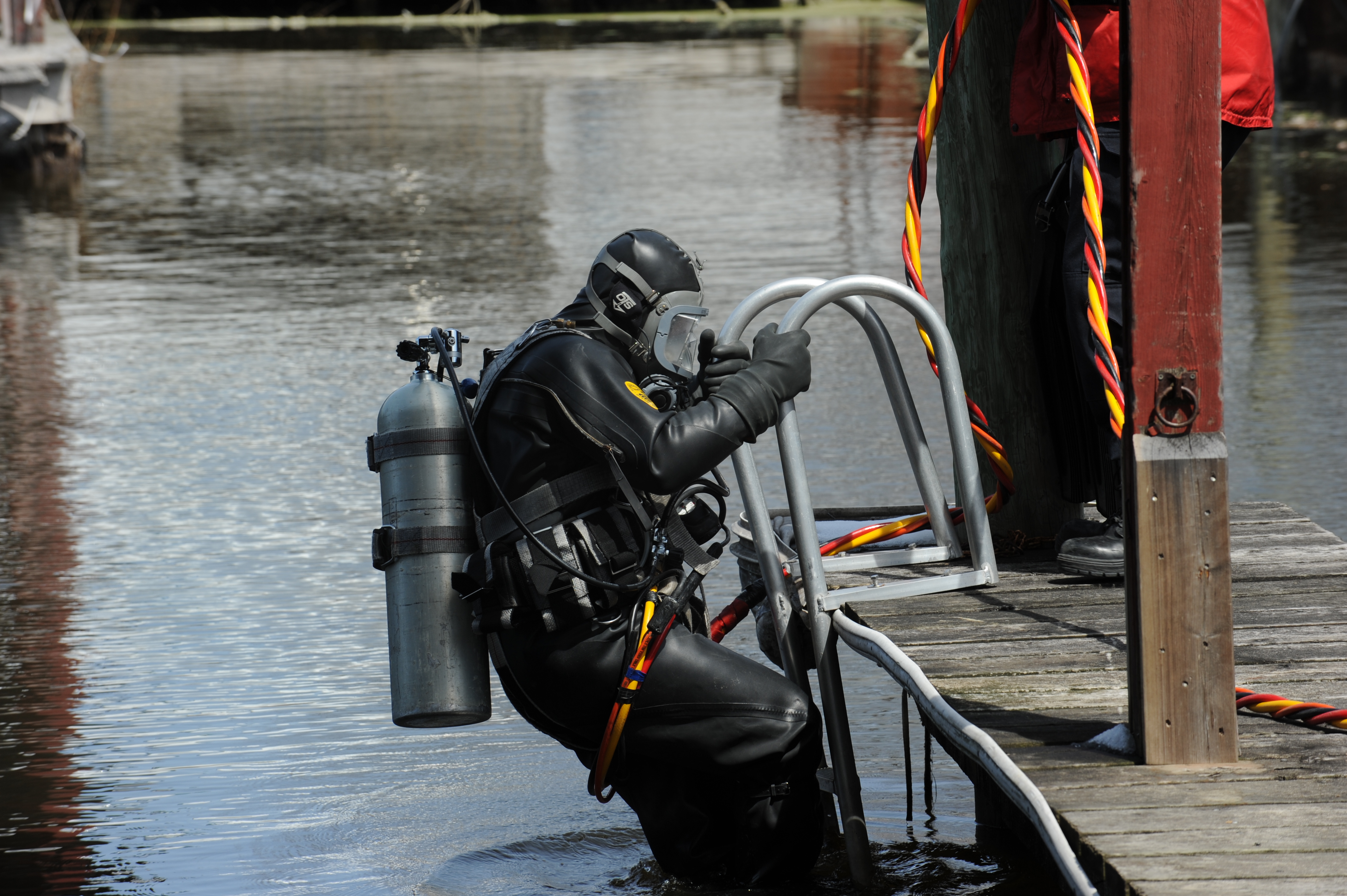 A man in a dive suit climbs a ladder