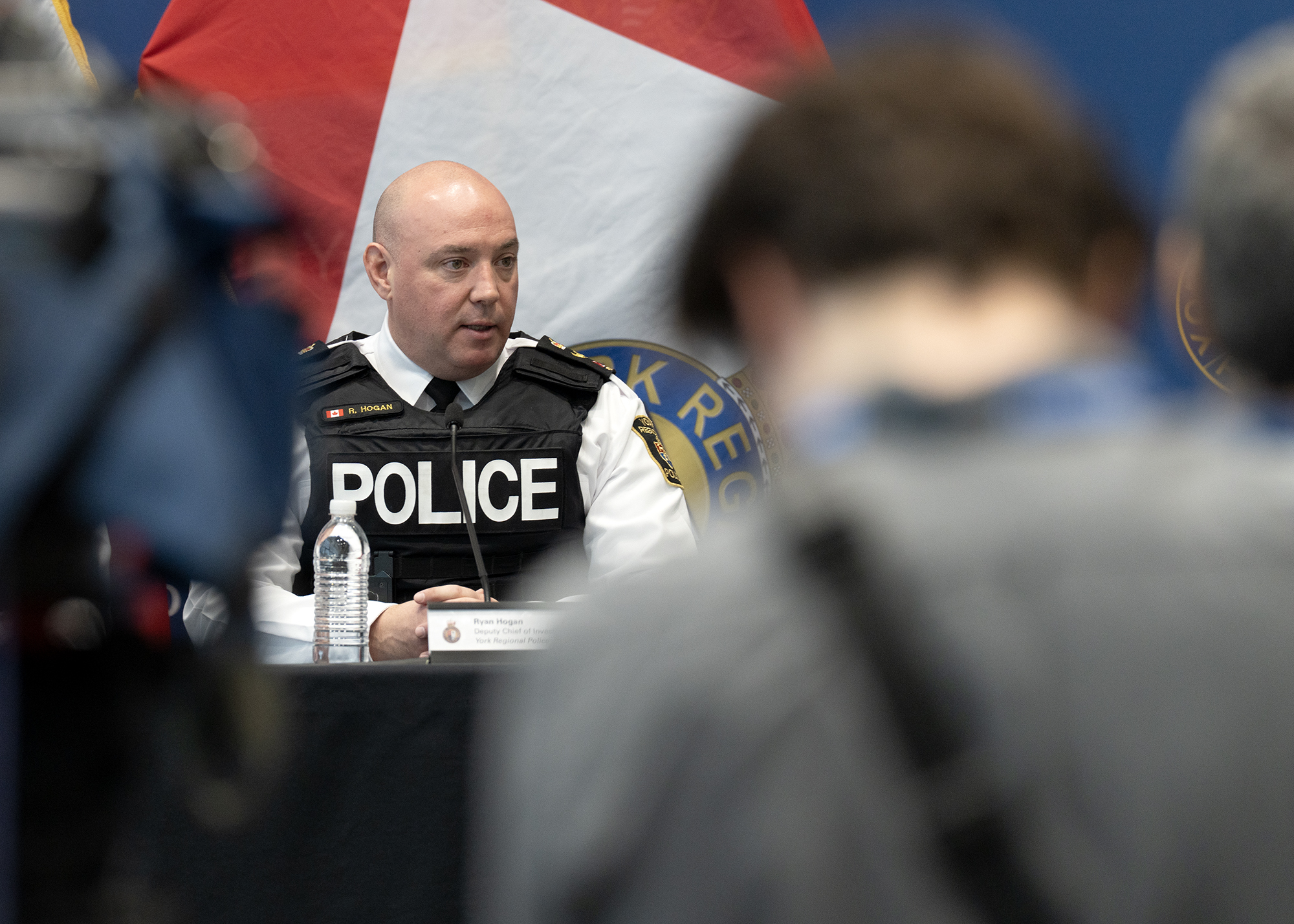 A man in a police uniform sits in front of a large crowd