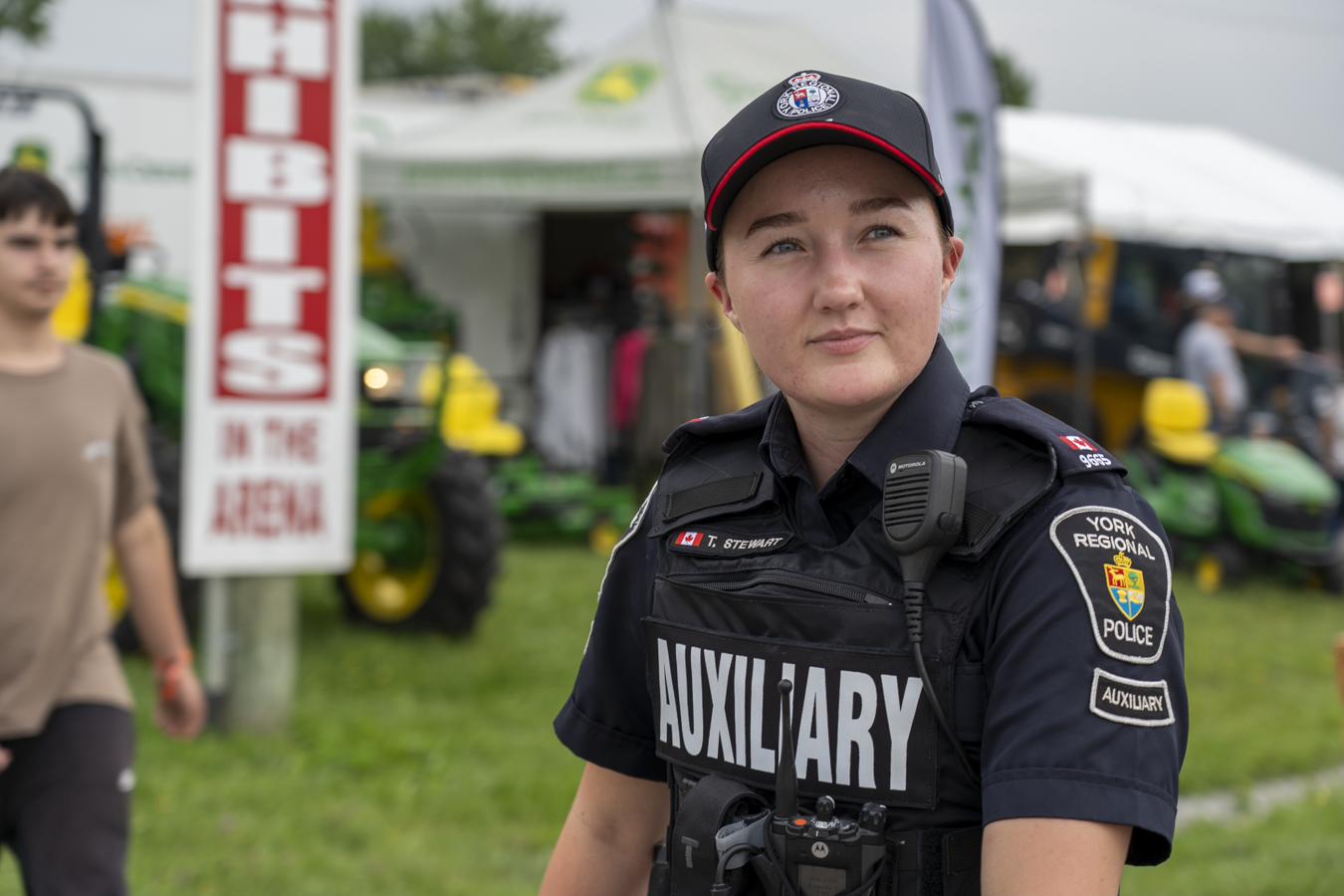 A female auxiliary constable sits in front of a tent at an event
