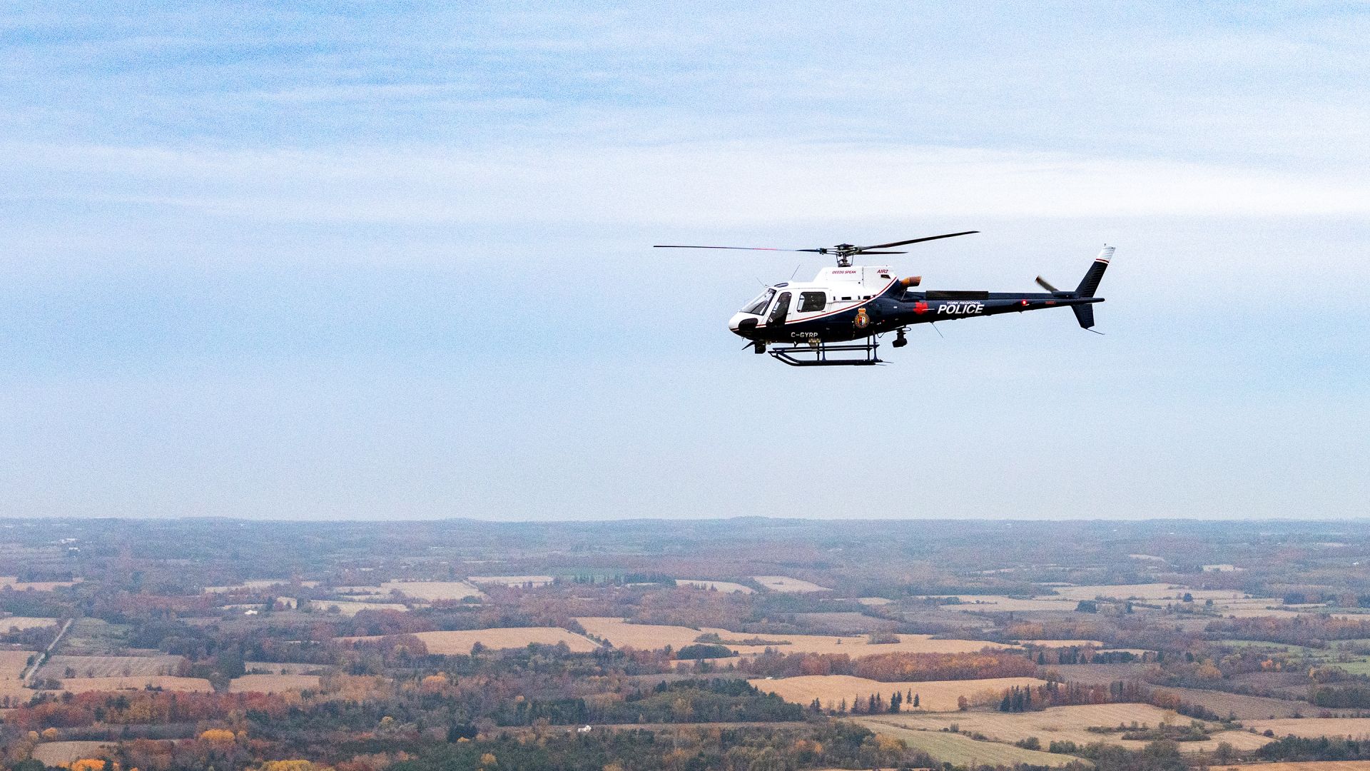 A helicopter flies over a rural landscape