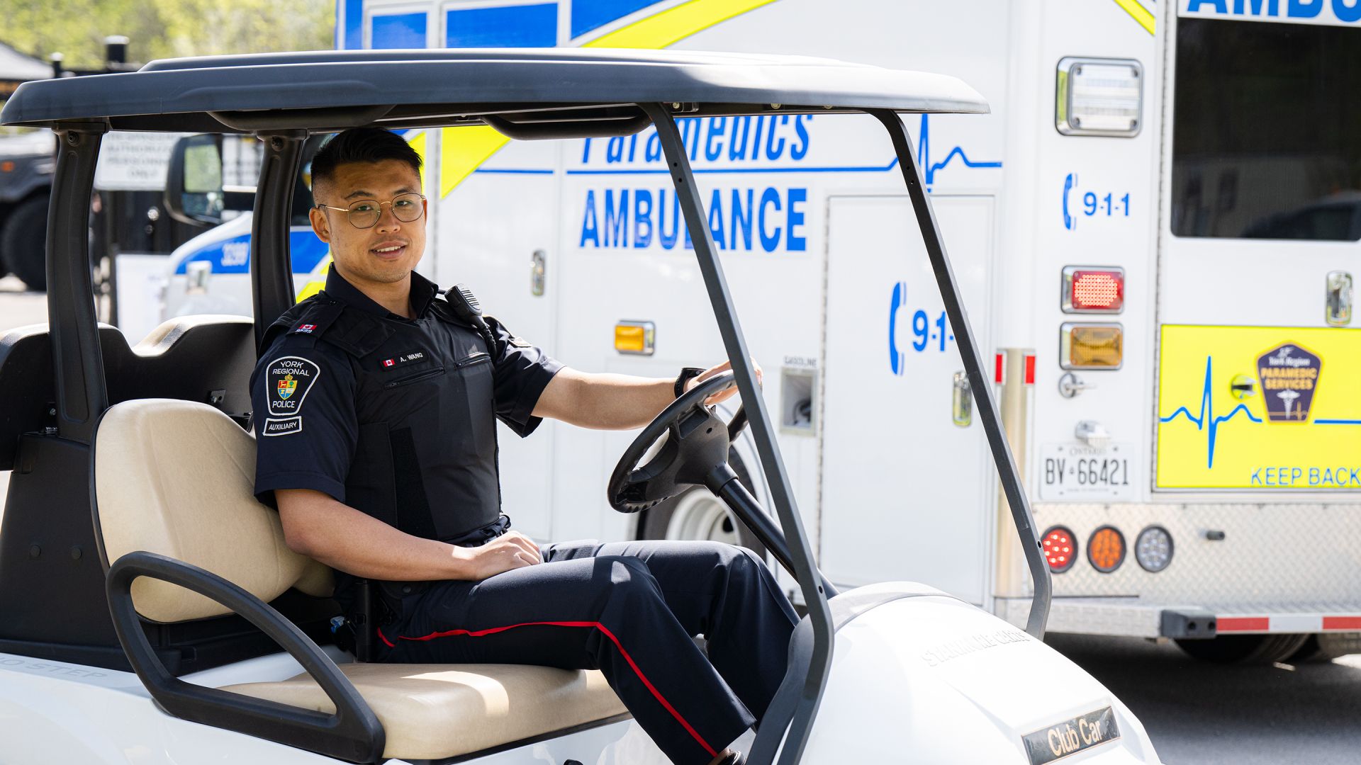 A man in a police uniform sits in a golf cart