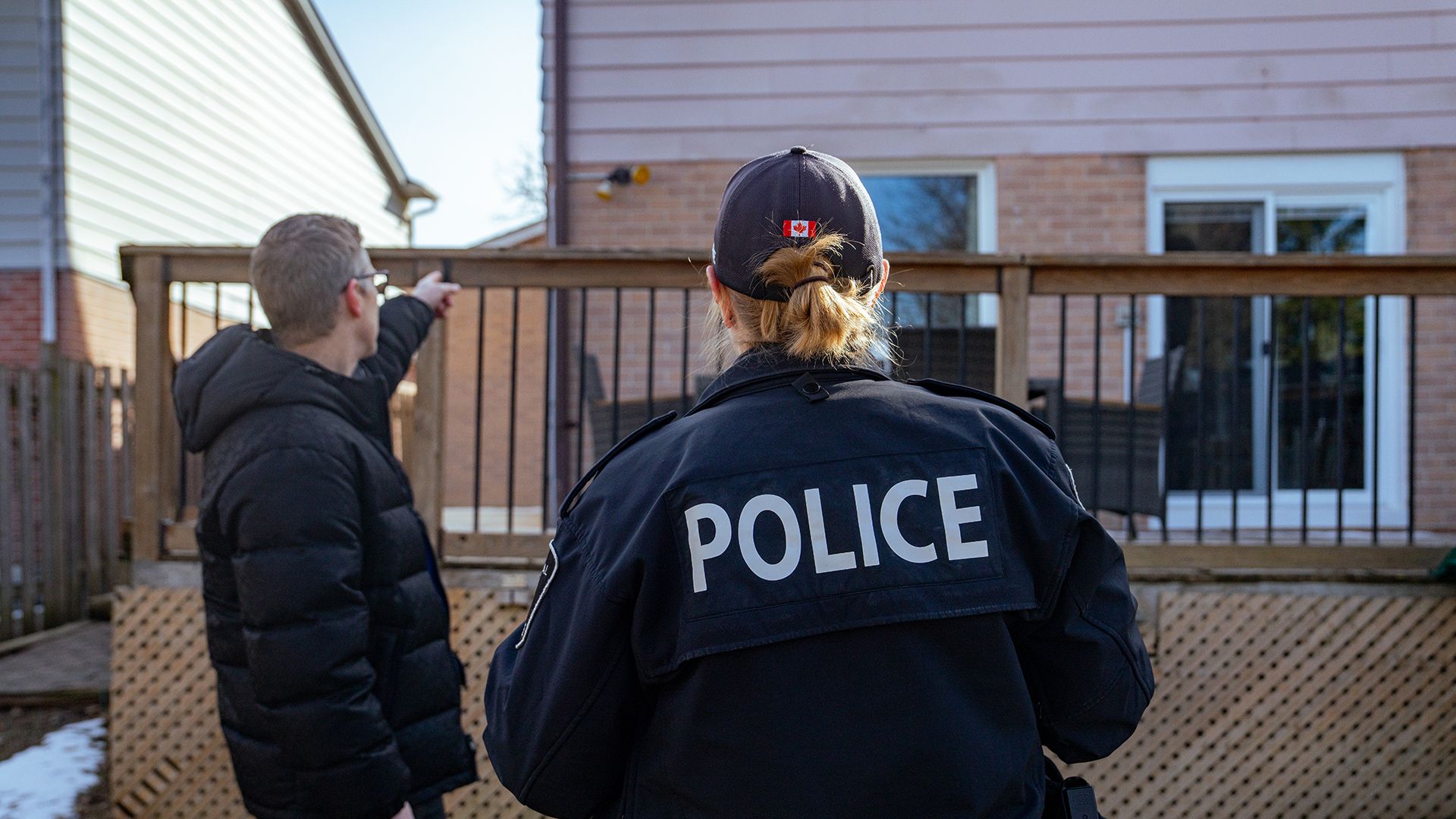 A police officer and a man look at the back of a home