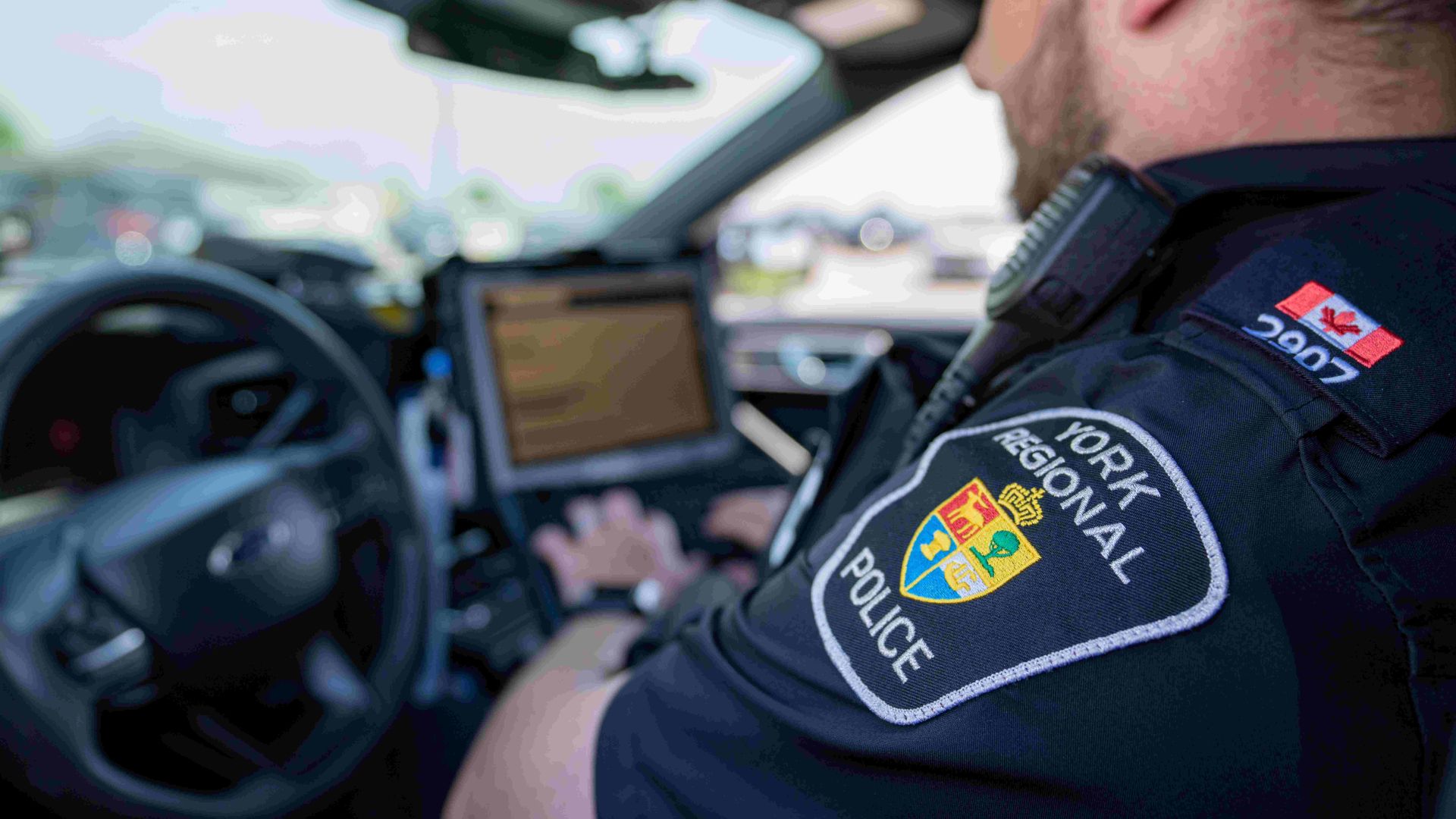 YRP badge officer typing in cruiser