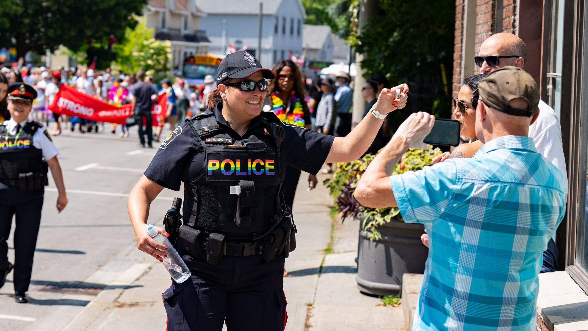 A woman in a police uniform hands out items at a parade