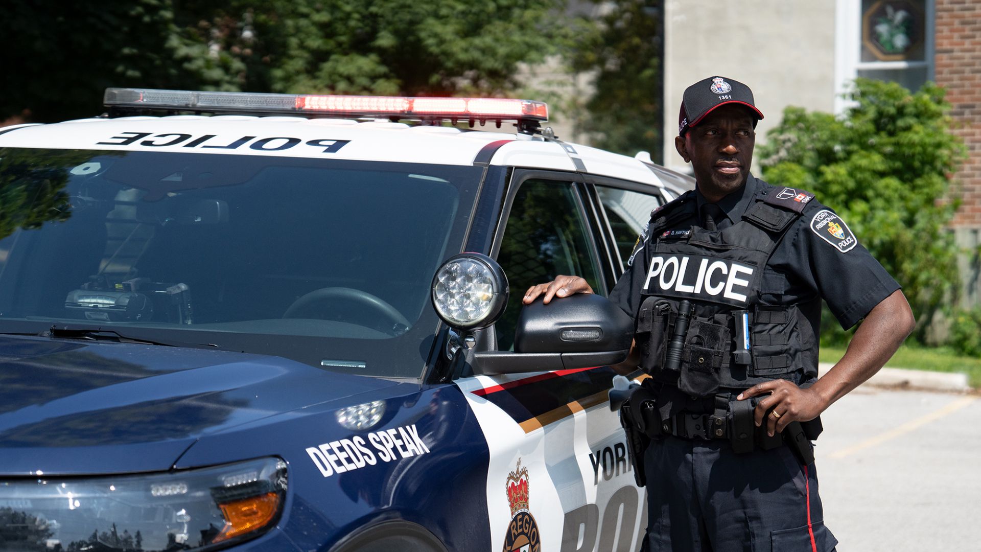 A man in a police uniform next to a police cruiser