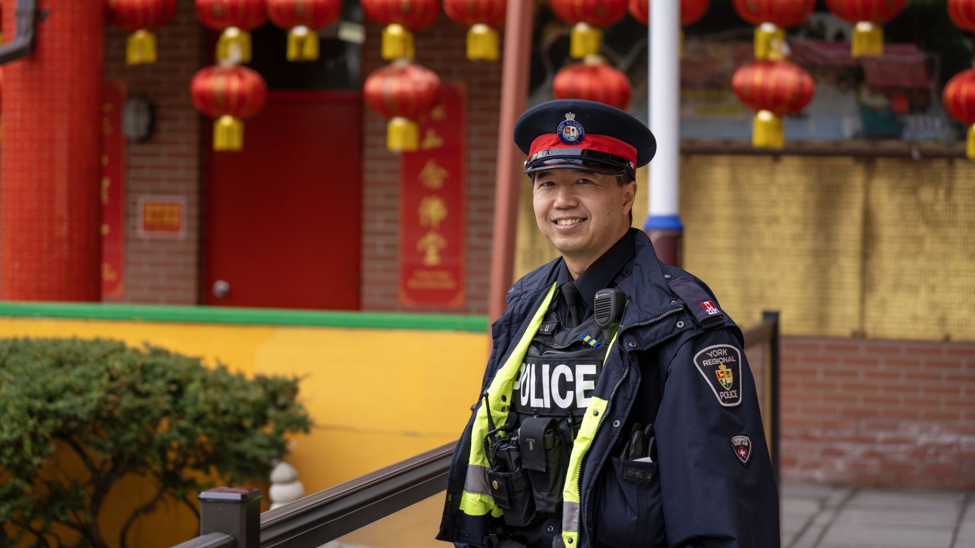 A man in a uniform smiles in front of lanterns