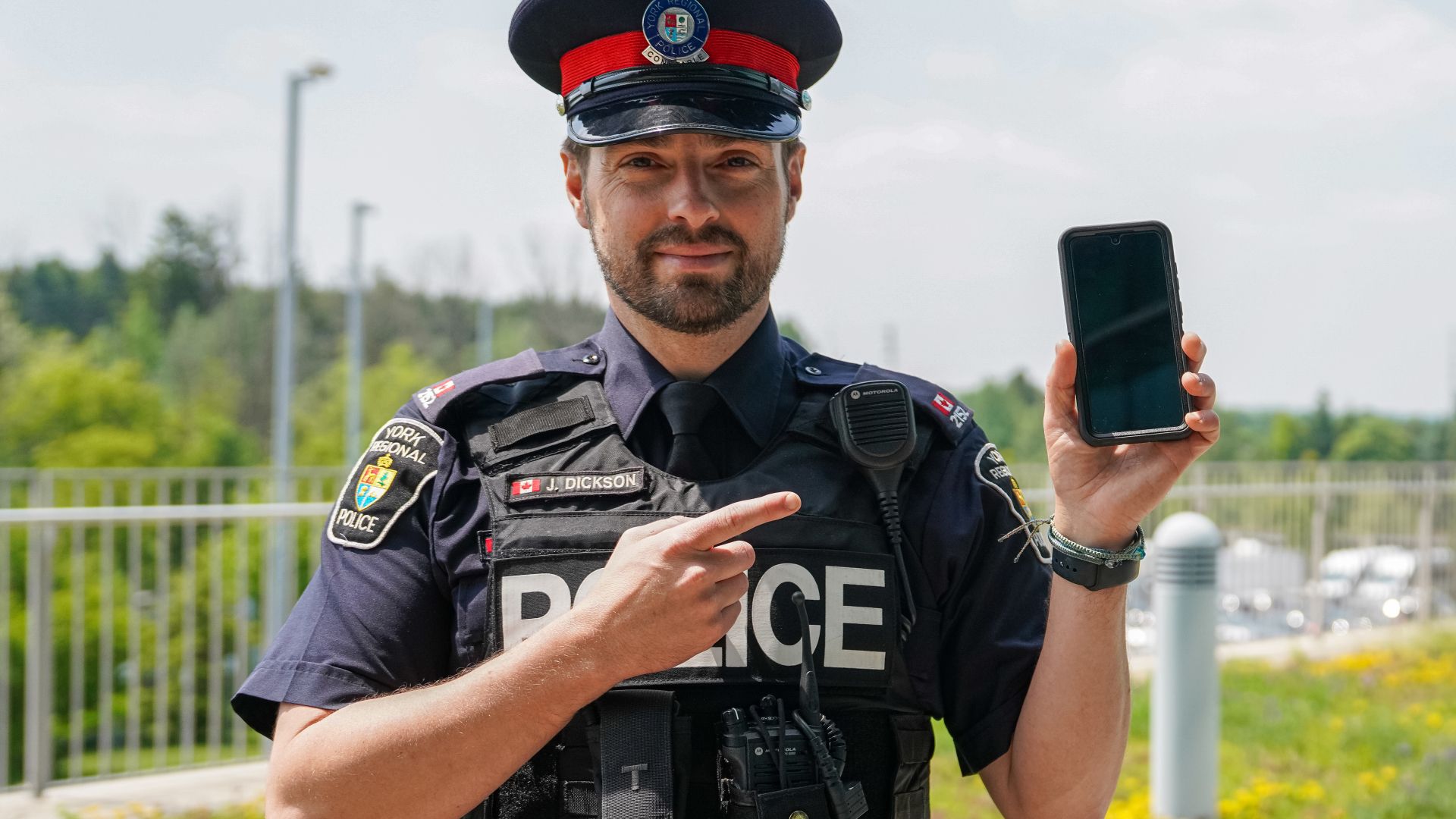A man in a police uniform holds a phone
