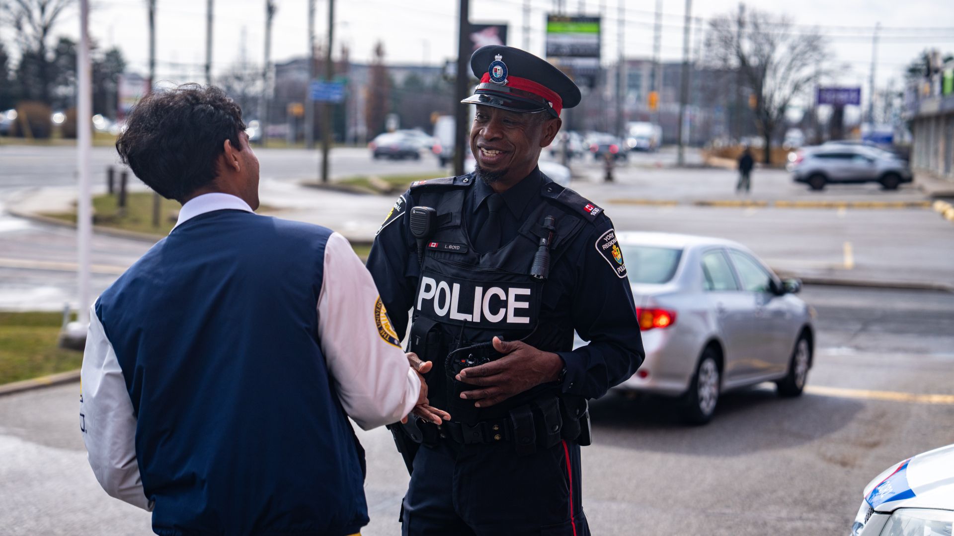 A man in a police uniform shakes another person's hand
