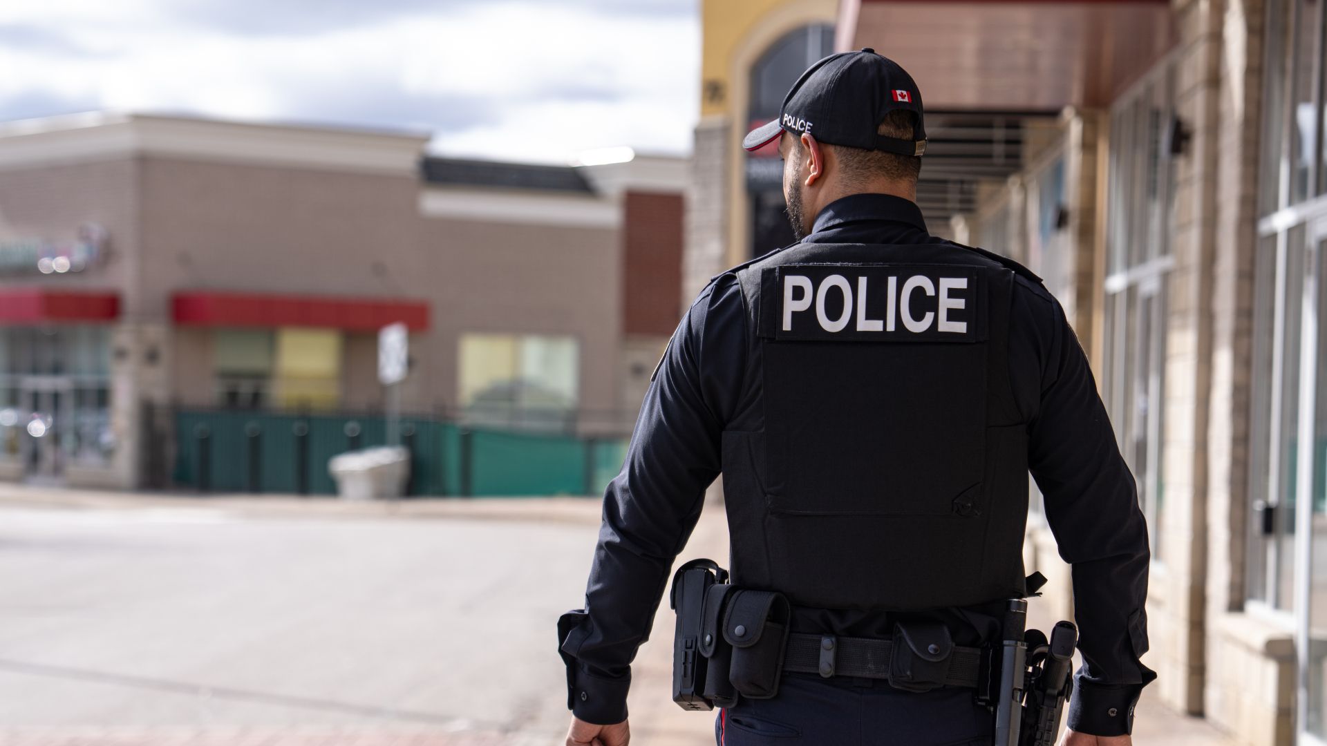 A man in a police uniform walks outside a plaza