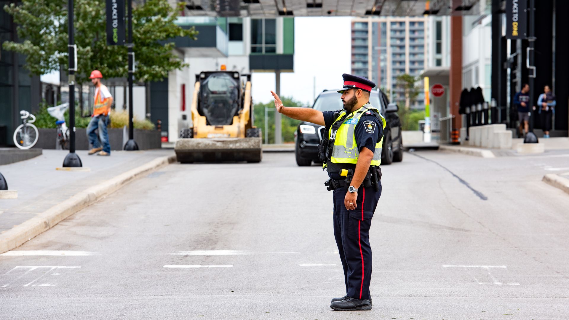 A police officer stands in an intersection and holds up his hand