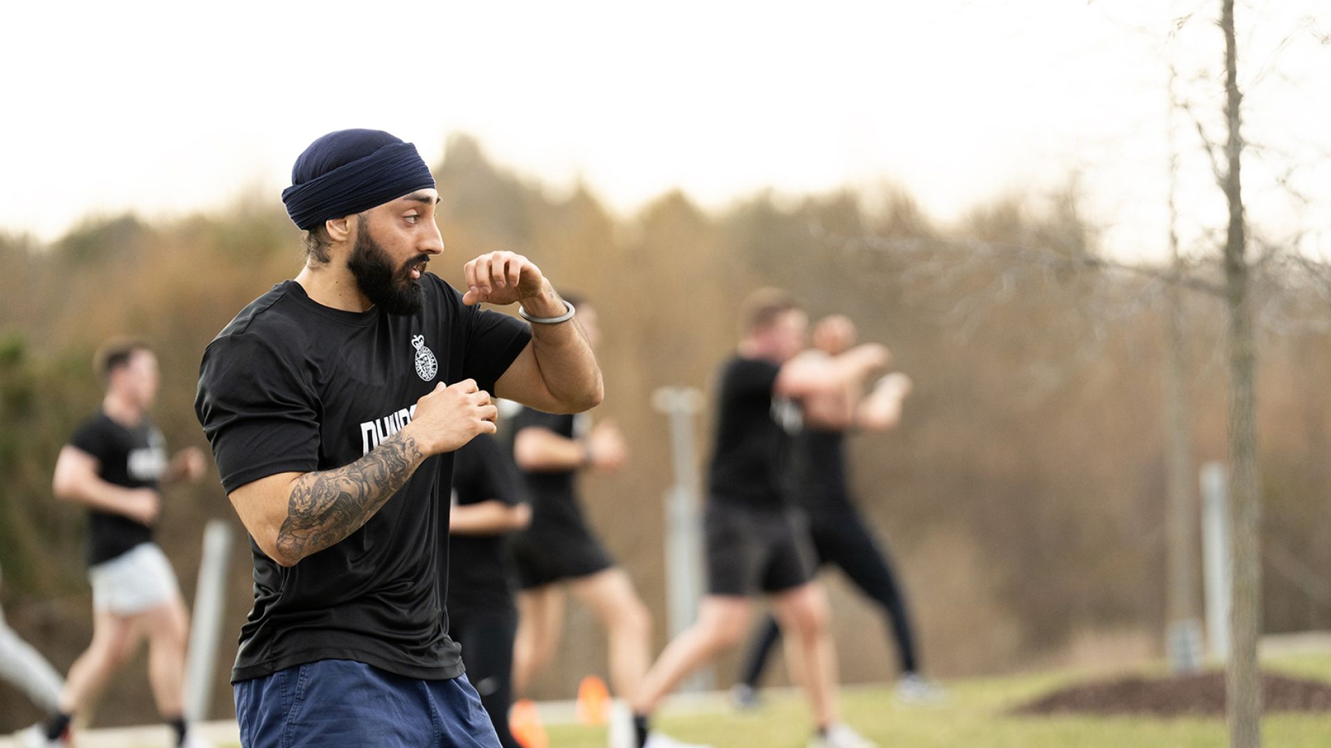 A man in gym clothes practices a stance with his arms up.