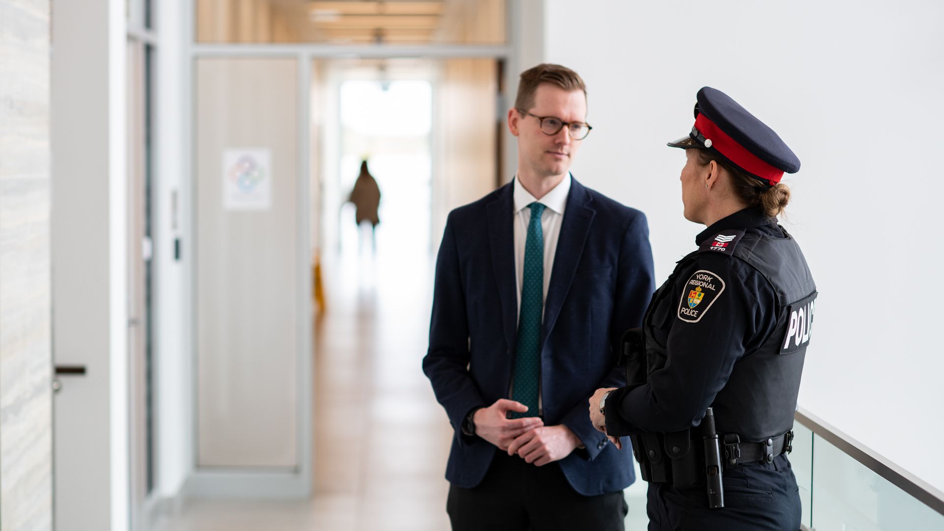 A man in a suit speaks with a woman in a uniform