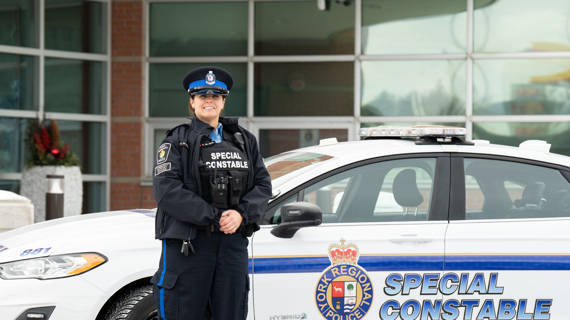 A woman smiles next to a car that reads SPECIAL CONSTABLE